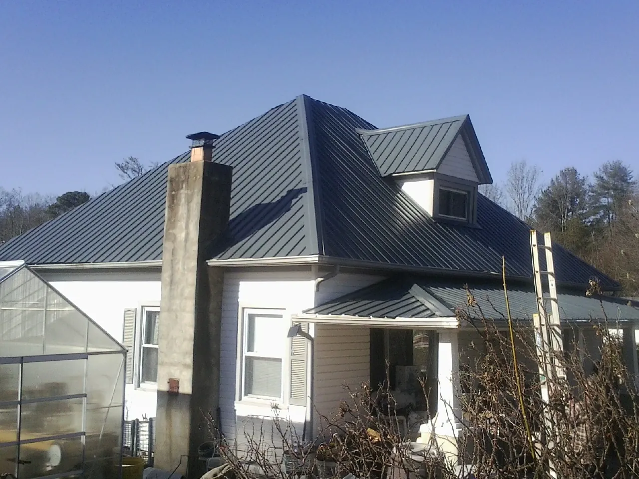Dark blue standing seam metal roof on a white farmhouse with dormer — Slate & Tile Roof Repair by Roofing Brothers in North Kingstown