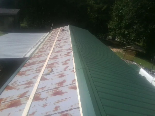 Old rusted panels beside newly installed green metal roofing — Wind Damage Roof Repair by Roofing Brothers in North Kingstown