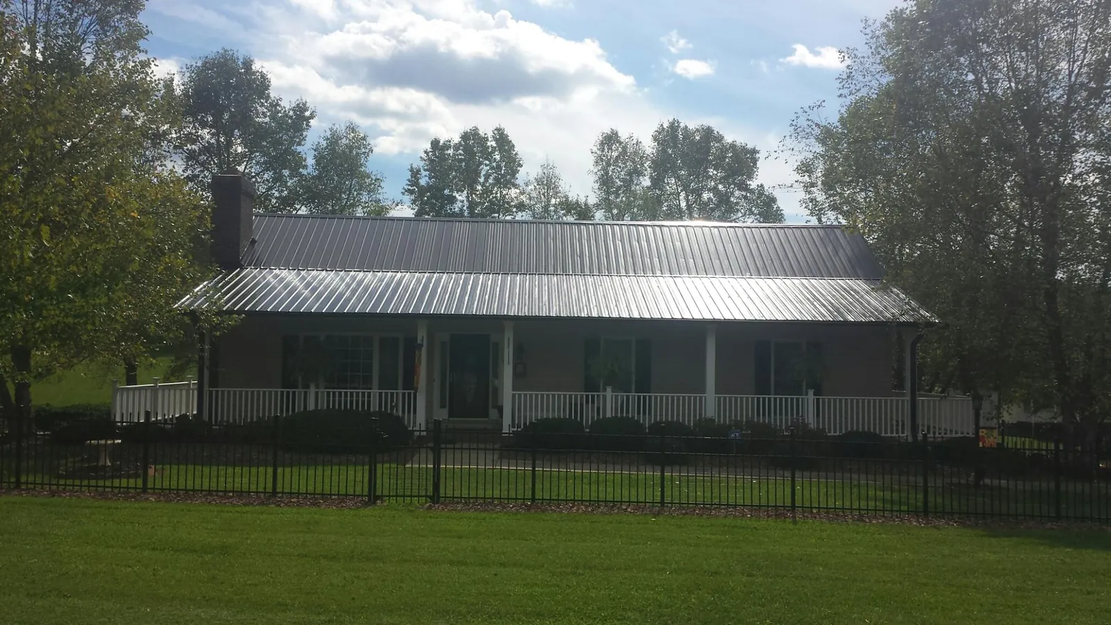 Gray metal roof on a brick ranch with a full width front porch — Gutter Guard Installation work by our crew in North Kingstown