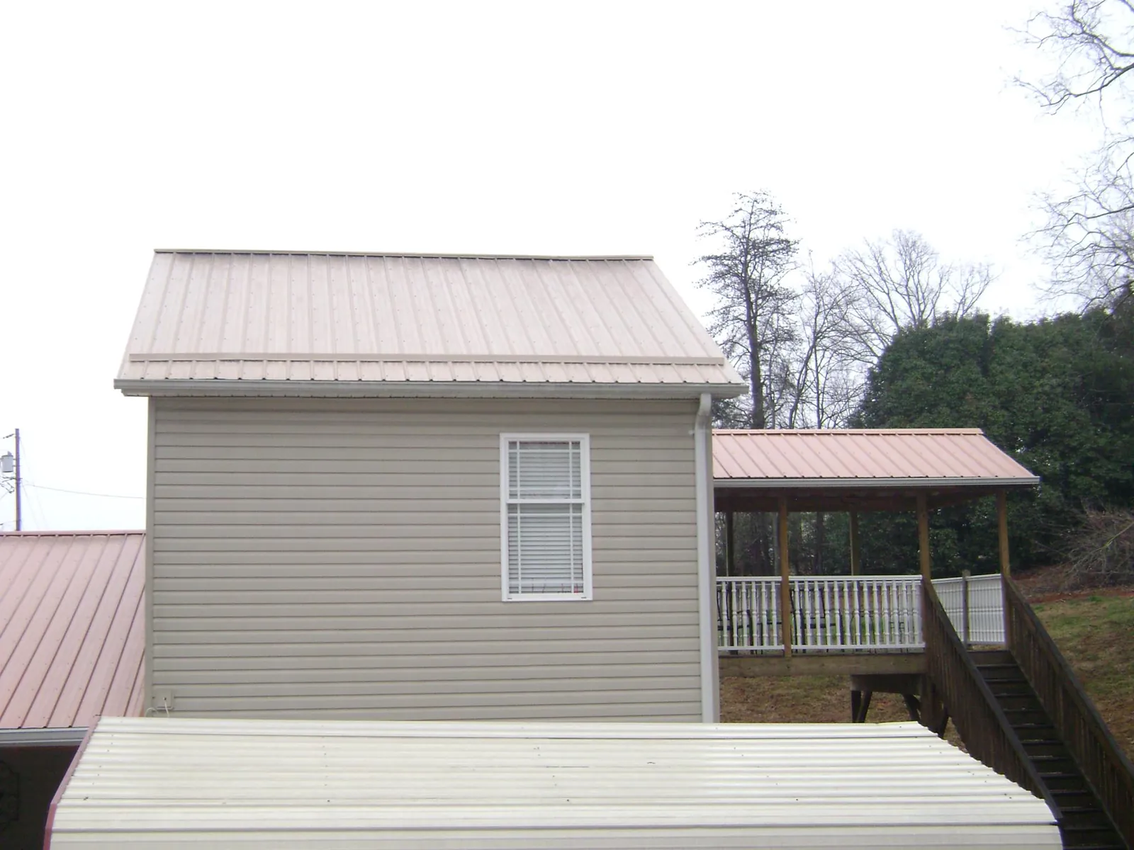 Tan metal roofs on a two story addition and attached porch, from a Roof Replacement job in North Kingstown