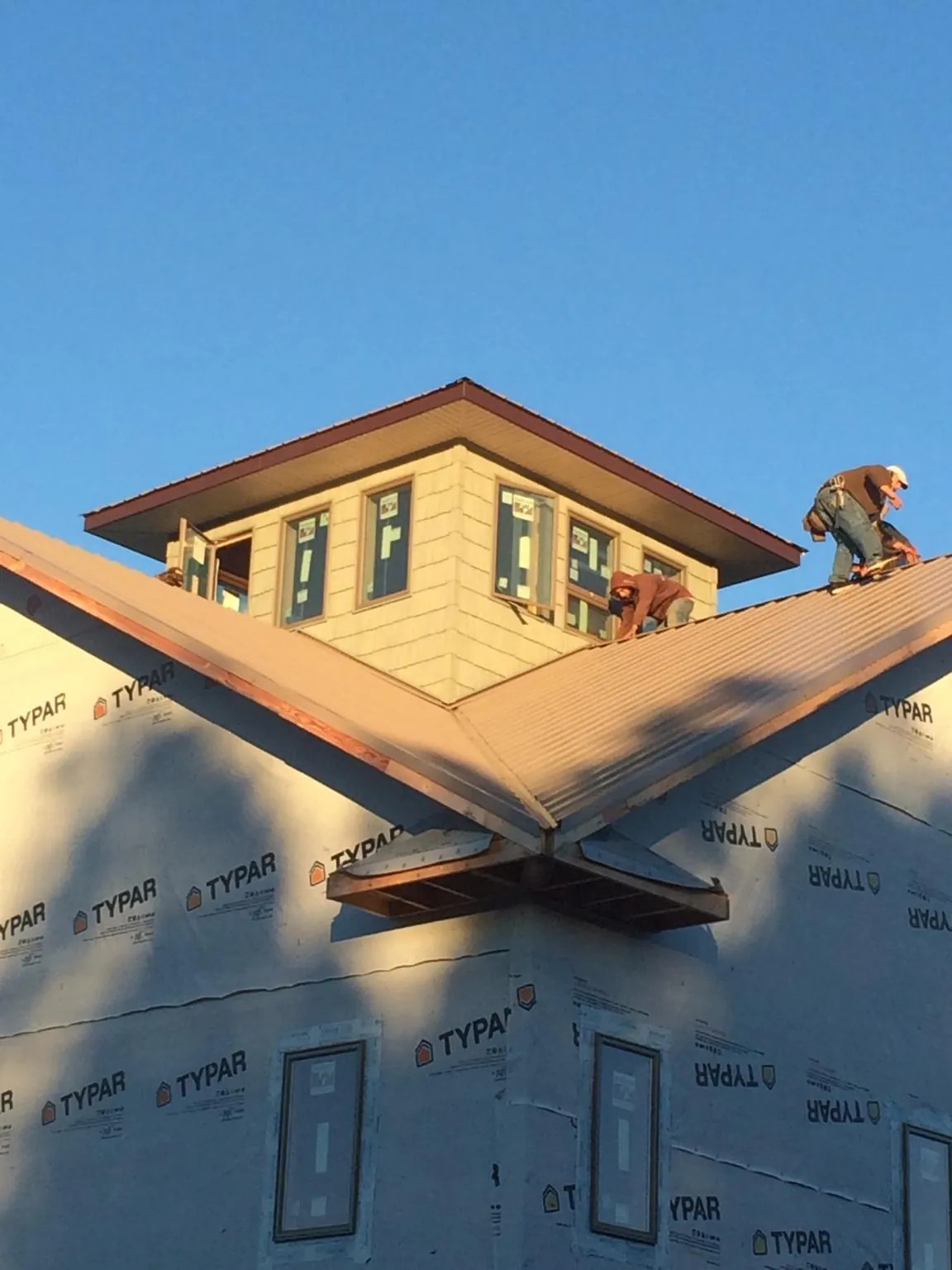 Roofers working around a rooftop cupola on a new metal roof at sunset — Roof Waterproofing in North Kingstown by Roofing Brothers